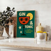 A gin and tonic cocktail with orange zest and green garnishes
