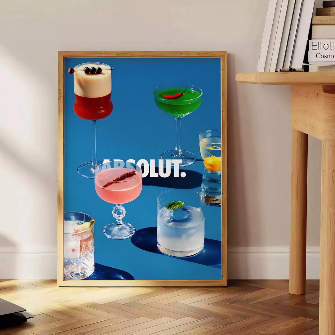 Poster of Absolut cocktail artwork in black and brown minimalist style - beside a round wooden side table with books