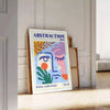 Maximalist abstract art featuring swirling shapes in blue and orange tones - leaning on a herringbone floor against a white panelled wall