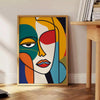 Poster mulher abstrata em laranja e vermelho, obra moderna expressiva para parede - ao lado de uma mesa de apoio redonda em madeira com livros