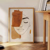 Poster showing abstract line art in green and orange, minimalist composition - beside a round wooden side table with books