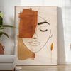Poster showing abstract line art in green and orange, minimalist composition - in a bright minimalist room with a plant and an armchair