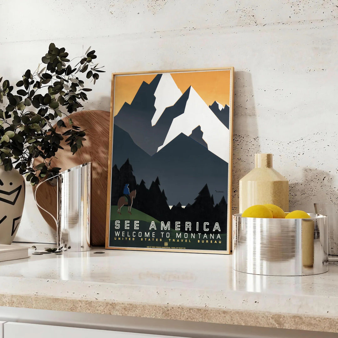 Vintage travel poster depicting Montana's green valleys under an orange sky - styled on a counter with eucalyptus and a bowl of lemons