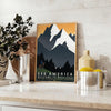 Vintage travel poster depicting Montana's green valleys under an orange sky - styled on a counter with eucalyptus and a bowl of lemons