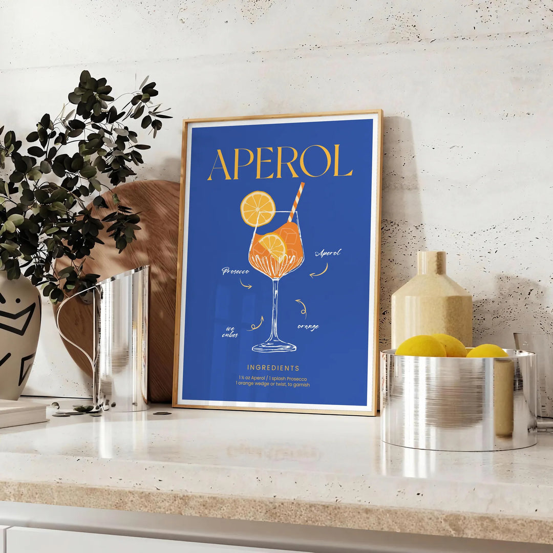 Aperol cocktail poster in bold blue and yellow modern abstract illustration - styled on a counter with eucalyptus and a bowl of lemons