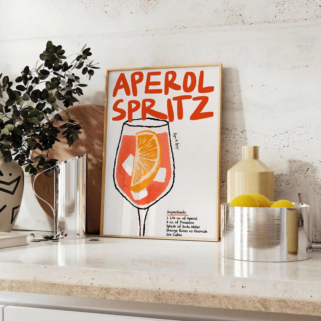 Poster raffigurante un Aperol Spritz stilizzato in arancione e nero - su un piano con eucalipto e una ciotola di limoni
