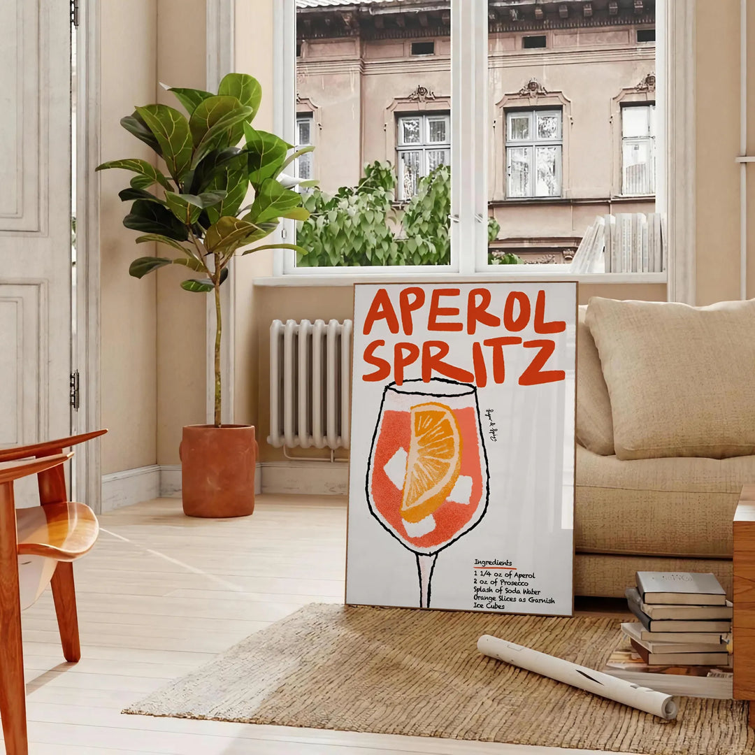 Poster raffigurante un Aperol Spritz stilizzato in arancione e nero - in un soggiorno parigino con divano e un ficus