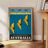 Vintage Australia travel poster with bold yellow and black graphics - beside a round wooden side table with books