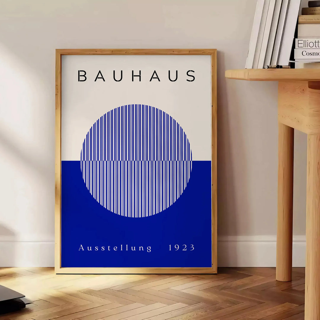Minimal Bauhaus poster showing geometric shapes and bold composition - beside a round wooden side table with books