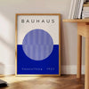 Minimal Bauhaus poster showing geometric shapes and bold composition - beside a round wooden side table with books