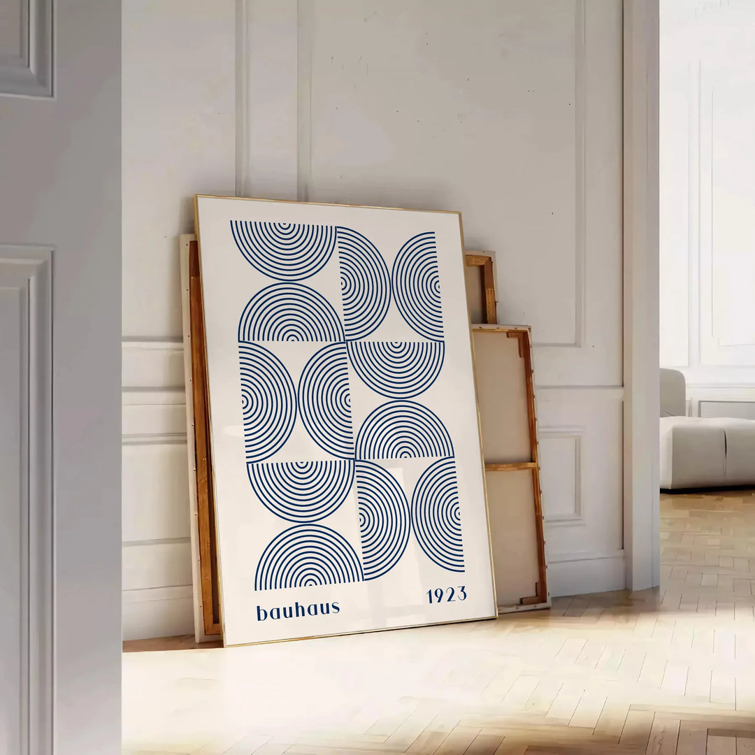 Bauhaus abstract poster with gray and blue geometric shapes, modern print - leaning on a herringbone floor against a white panelled wall