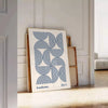 Bauhaus abstract poster with gray and blue geometric shapes, modern print - leaning on a herringbone floor against a white panelled wall