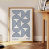 Bauhaus abstract poster with gray and blue geometric shapes, modern print - beside a round wooden side table with books