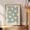 Poster showing Bauhaus abstract geometric composition in minimalist modern style - beside a round wooden side table with books