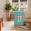 Bauhaus geometric abstract poster with bold red, blue, yellow shapes - in a Parisian living room with a sofa and a fig plant