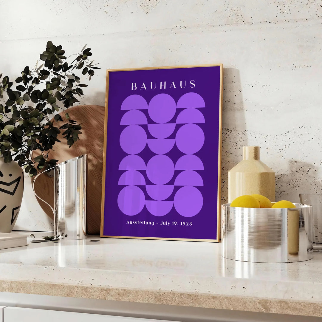 Purple and white geometric Bauhaus poster, bold minimalist shapes on paper - styled on a counter with eucalyptus and a bowl of lemons
