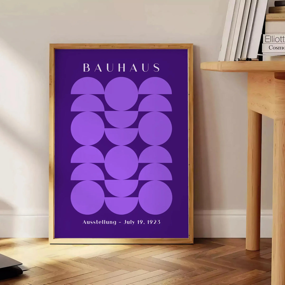 Purple and white geometric Bauhaus poster, bold minimalist shapes on paper - beside a round wooden side table with books