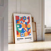 Bauhaus geometric abstract poster with orange and blue minimalist shapes - leaning on a herringbone floor against a white panelled wall