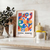 Bauhaus geometric abstract poster with orange and blue minimalist shapes - styled on a counter with eucalyptus and a bowl of lemons