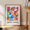Bauhaus geometric abstract poster with orange and blue minimalist shapes - beside a round wooden side table with books
