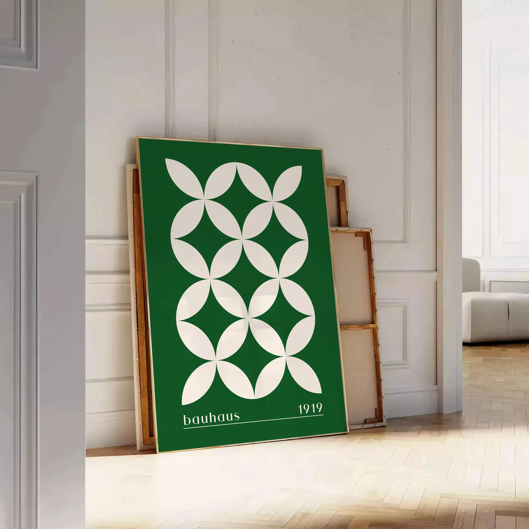 Green and white poster featuring abstract geometric shapes in Bauhaus style - leaning on a herringbone floor against a white panelled wall