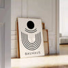 Poster Bauhaus geometrico grigio e nero con forme astratte minimaliste - appoggiato su un pavimento a spina di pesce contro una parete a pannelli