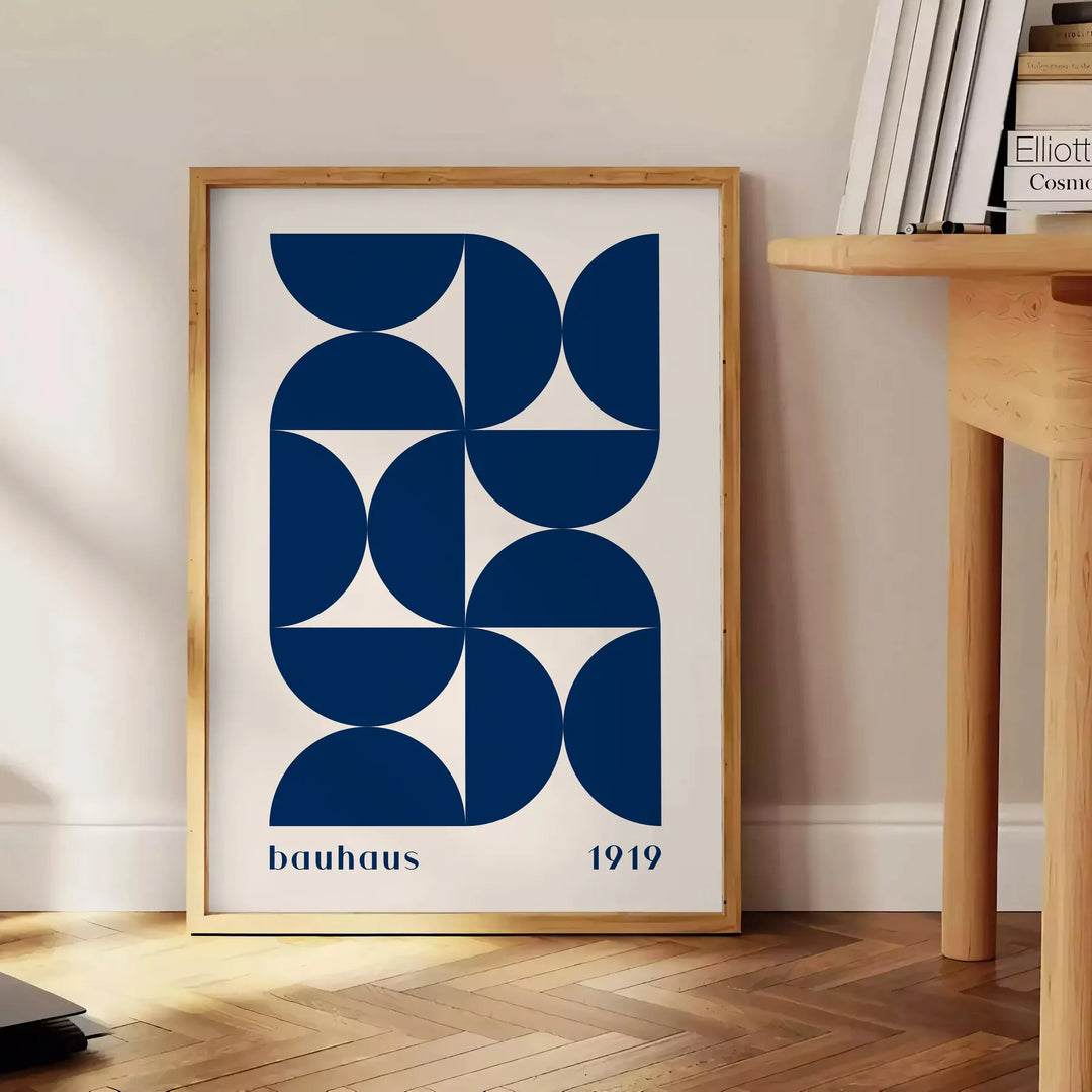 Vintage Bauhaus poster featuring geometric shapes in muted colors - beside a round wooden side table with books