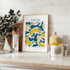 Gray and orange minimalist banana kitchen art poster, modern playful design - styled on a counter with eucalyptus and a bowl of lemons