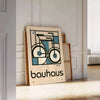 Minimalist poster of a bicycle in Bauhaus style with geometric shapes - leaning on a herringbone floor against a white panelled wall