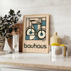 Minimalist poster of a bicycle in Bauhaus style with geometric shapes - styled on a counter with eucalyptus and a bowl of lemons