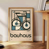 Minimalist poster of a bicycle in Bauhaus style with geometric shapes - beside a round wooden side table with books