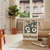 Minimalist poster of a bicycle in Bauhaus style with geometric shapes - in a Parisian living room with a sofa and a fig plant