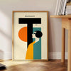 Poster mit minimalistischer geometrischer Menschendarstellung im klassischen Bauhaus-Stil - neben einem runden Beistelltisch aus Holz mit Büchern