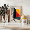 Bauhaus poster featuring a stylized human figure in orange and black - styled on a counter with eucalyptus and a bowl of lemons