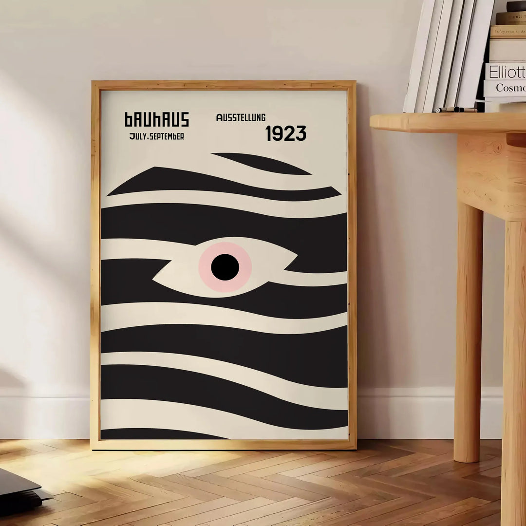 Poster showing geometric abstract Bauhaus composition with bold shapes - beside a round wooden side table with books
