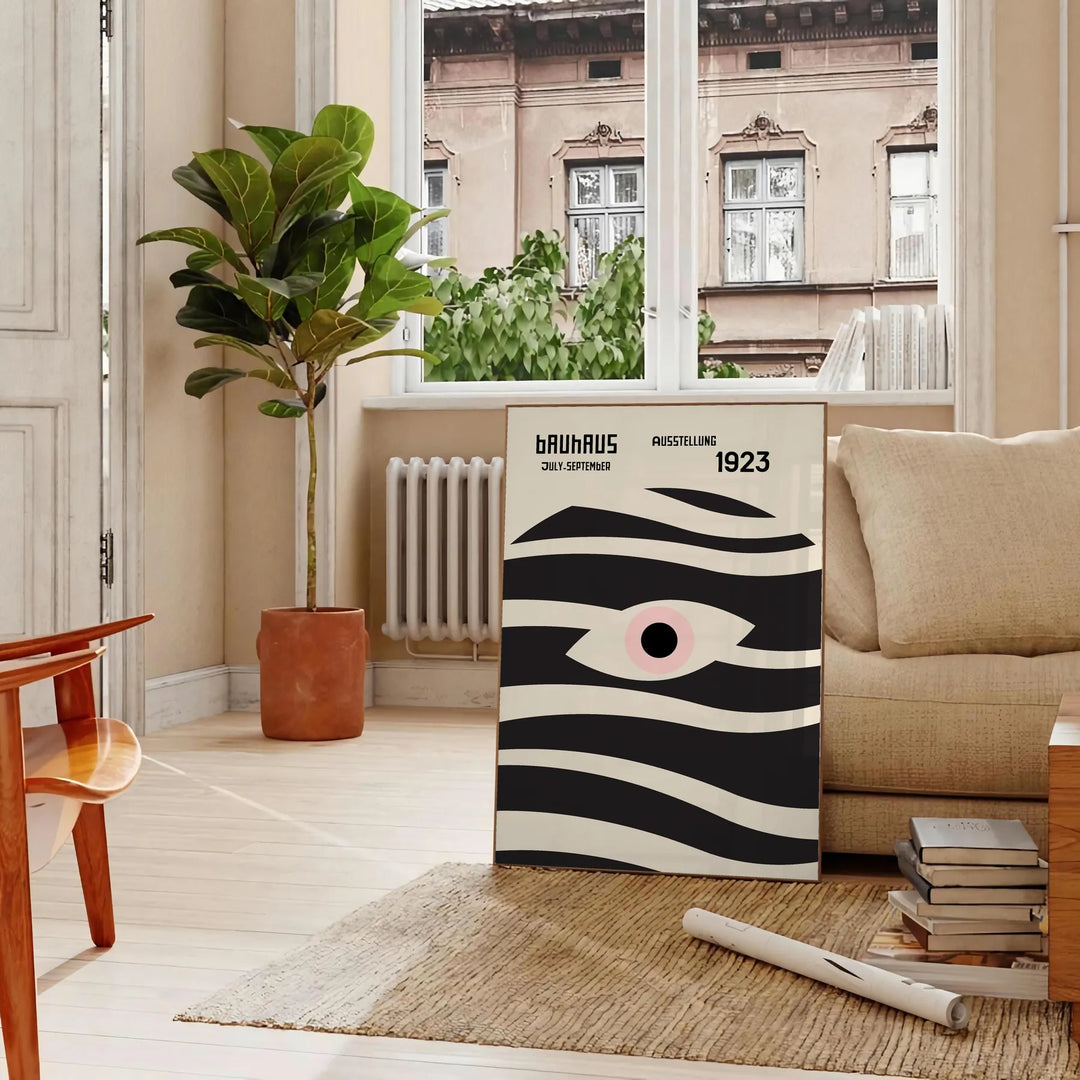 Poster showing geometric abstract Bauhaus composition with bold shapes - in a Parisian living room with a sofa and a fig plant