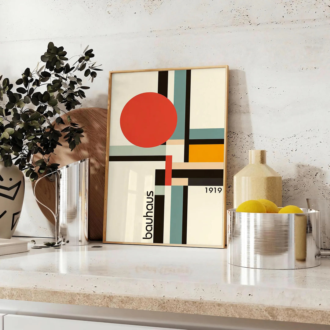 Bauhaus-Poster mit geometrischem Design in Orange und Schwarz - auf einer Arbeitsplatte mit Eukalyptus und einer Schale Zitronen