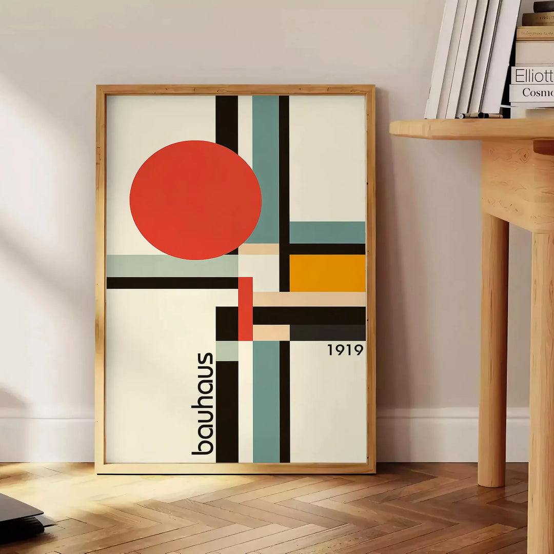 Bauhaus-Poster mit geometrischem Design in Orange und Schwarz - neben einem runden Beistelltisch aus Holz mit Büchern