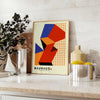 Cartel Bauhaus con diseño geométrico abstracto en rojo y naranja - sobre una encimera con eucalipto y un cuenco de limones