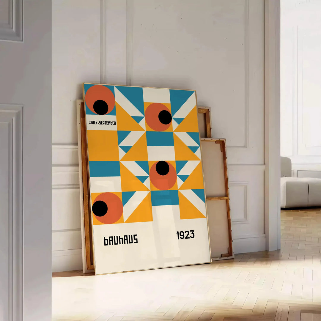 Bauhaus-style abstract geometric poster in orange and blue - leaning on a herringbone floor against a white panelled wall