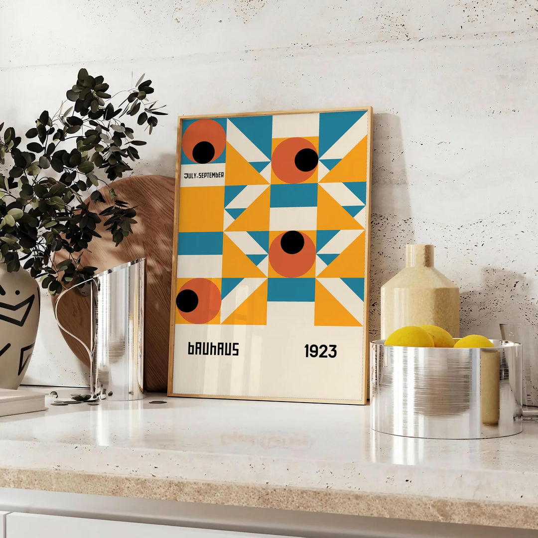 Bauhaus-style abstract geometric poster in orange and blue - styled on a counter with eucalyptus and a bowl of lemons