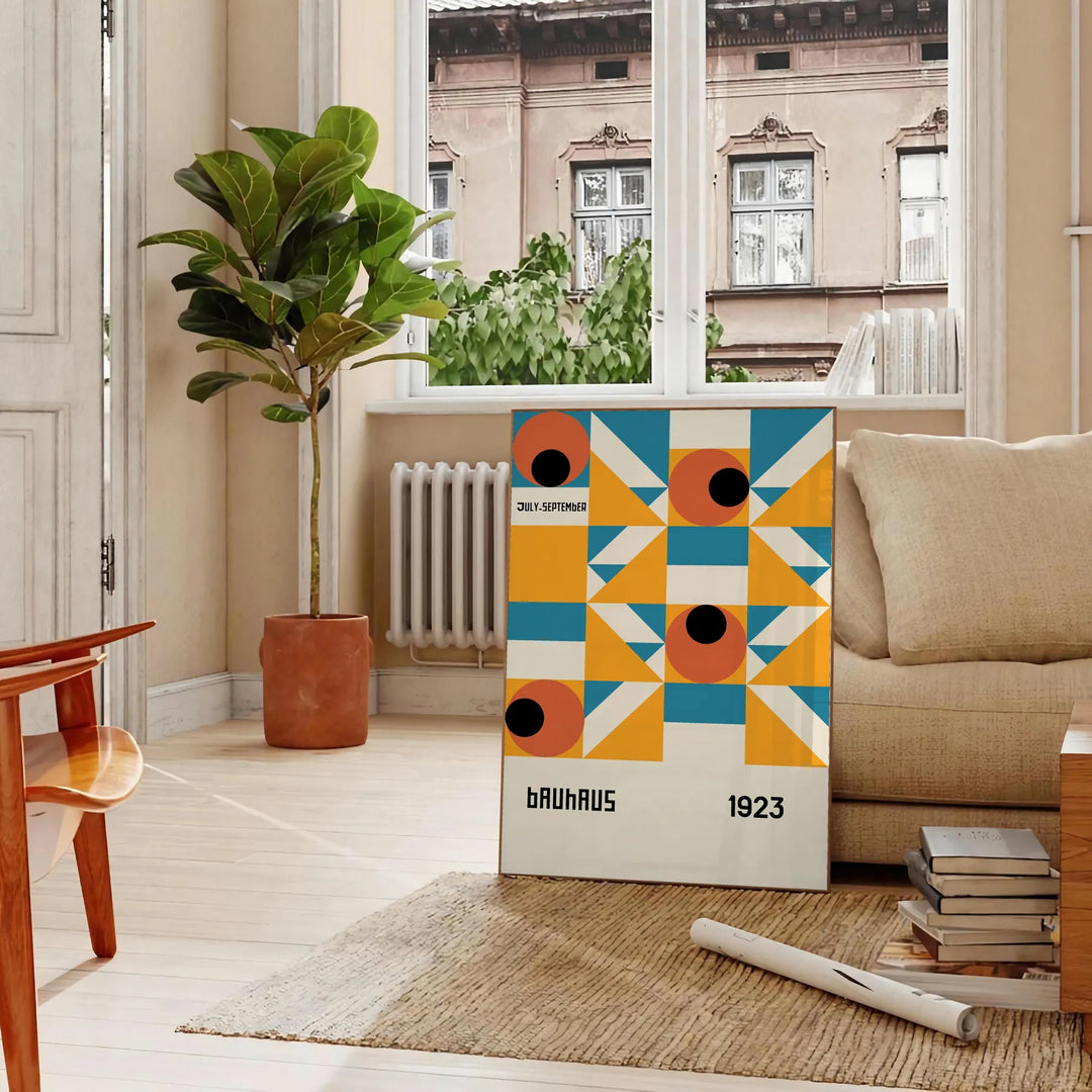 Bauhaus-style abstract geometric poster in orange and blue - in a Parisian living room with a sofa and a fig plant