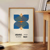 Bauhaus poster showing abstract geometric composition in minimalist modernist style - beside a round wooden side table with books