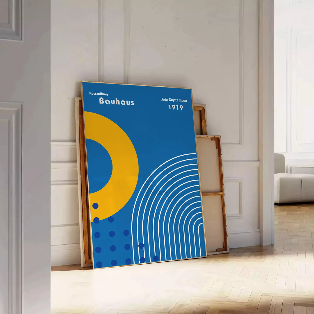 Minimalistyczny plakat Bauhaus z szarymi i żółtymi kształtami geometrycznymi - oparty na podłodze jodełkowej przy białej ścianie z paneli
