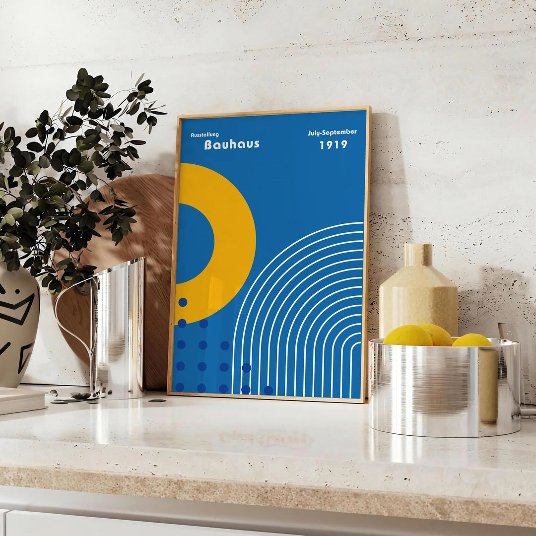 Minimalistyczny plakat Bauhaus z szarymi i żółtymi kształtami geometrycznymi - na blacie z eukaliptusem i miską cytryn