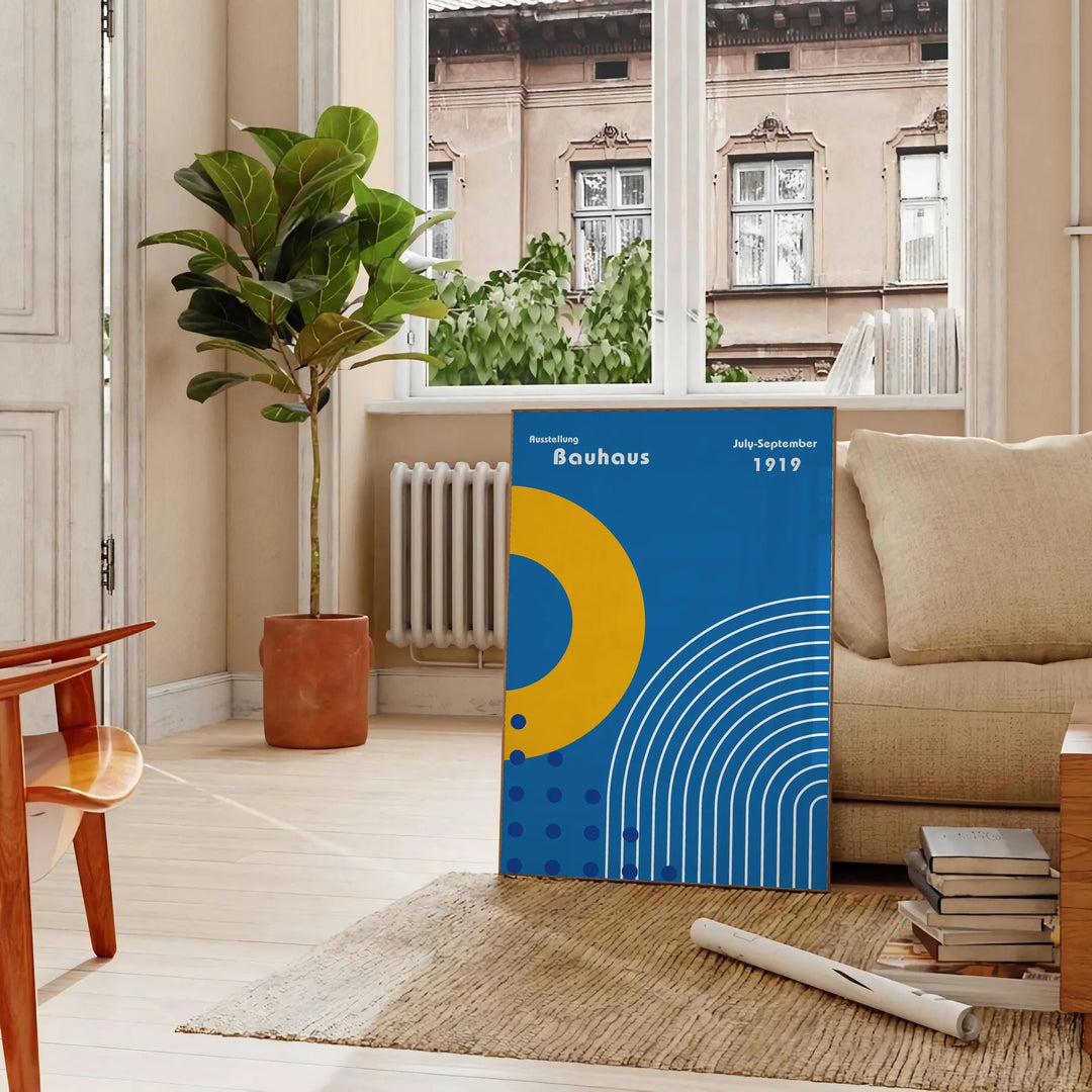 Minimalistyczny plakat Bauhaus z szarymi i żółtymi kształtami geometrycznymi - w paryskim salonie z sofą i fikusem