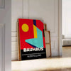 Bauhaus geometric poster in bold red and yellow abstract shapes - leaning on a herringbone floor against a white panelled wall