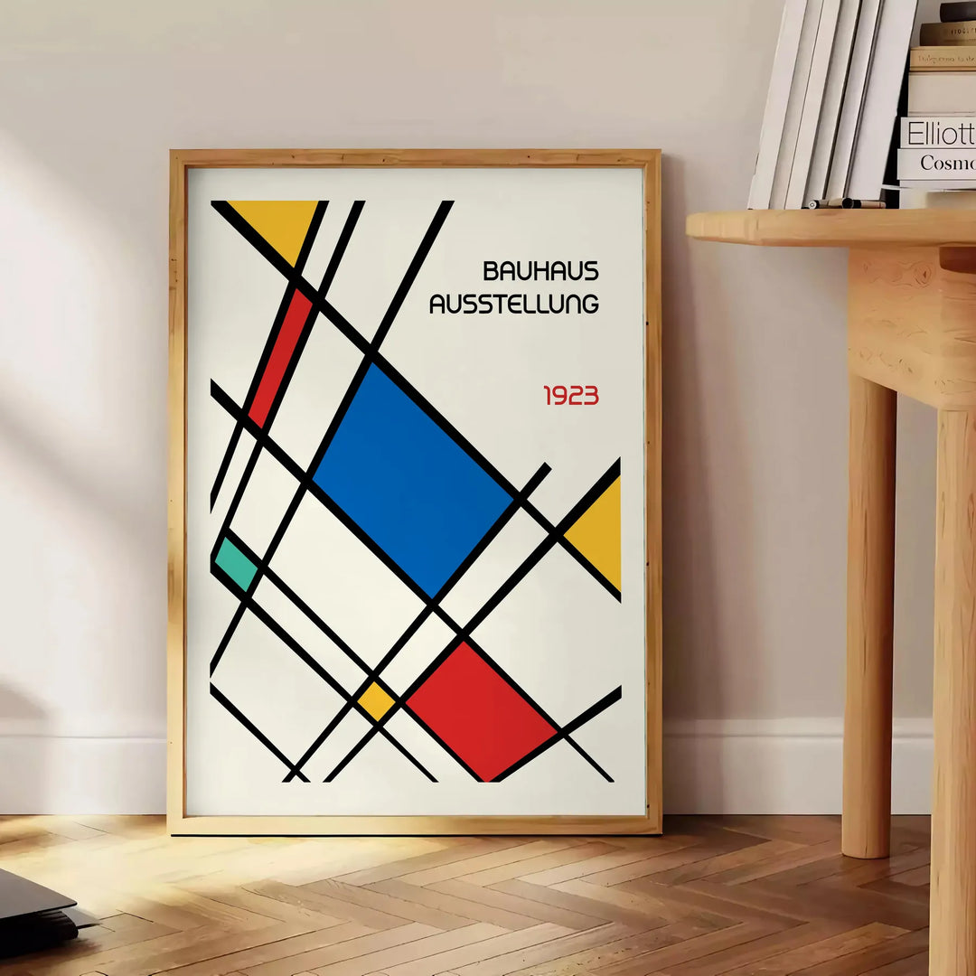 White and red geometric Bauhaus poster with bold minimalist abstract composition - beside a round wooden side table with books