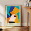 Bauhaus poster with geometric orange and green abstract shapes, modern style - beside a round wooden side table with books