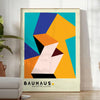 Bauhaus poster with geometric orange and green abstract shapes, modern style - in a bright minimalist room with a plant and an armchair